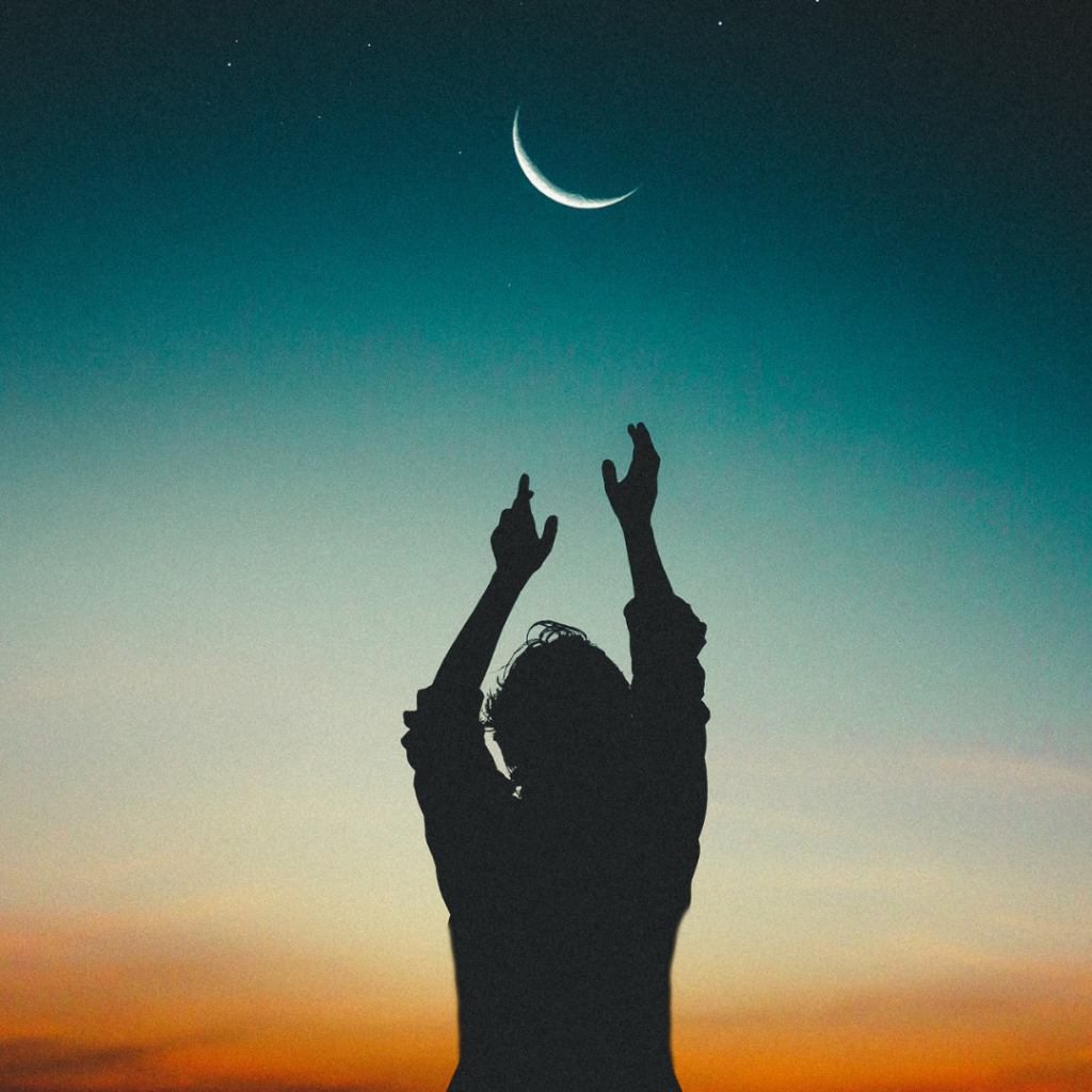 woman dances with her hands in the air under the moon