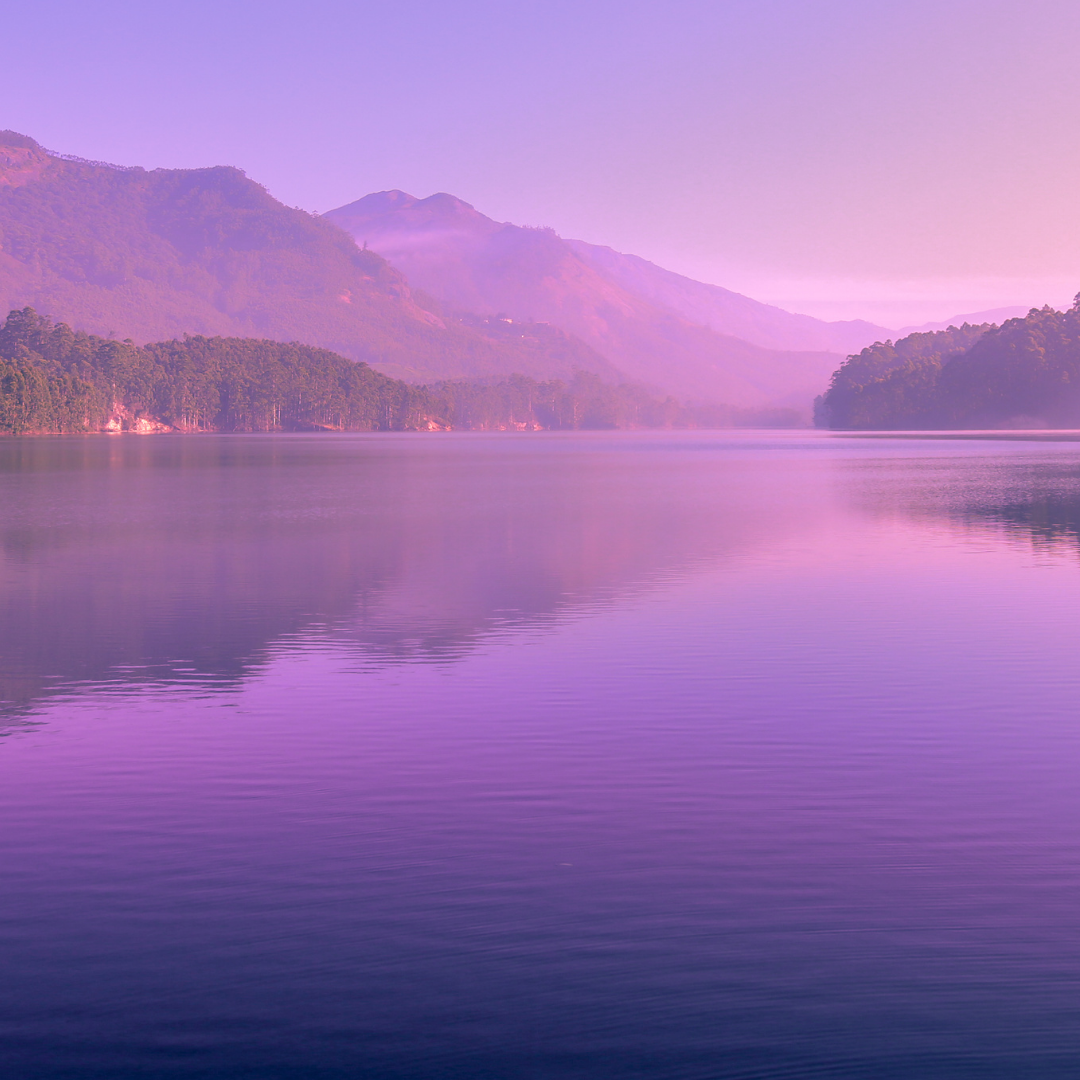 a picture of mountains looking over a large body of water with a purple hue