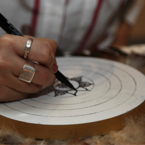 a woman drawing a sun onto a mandala