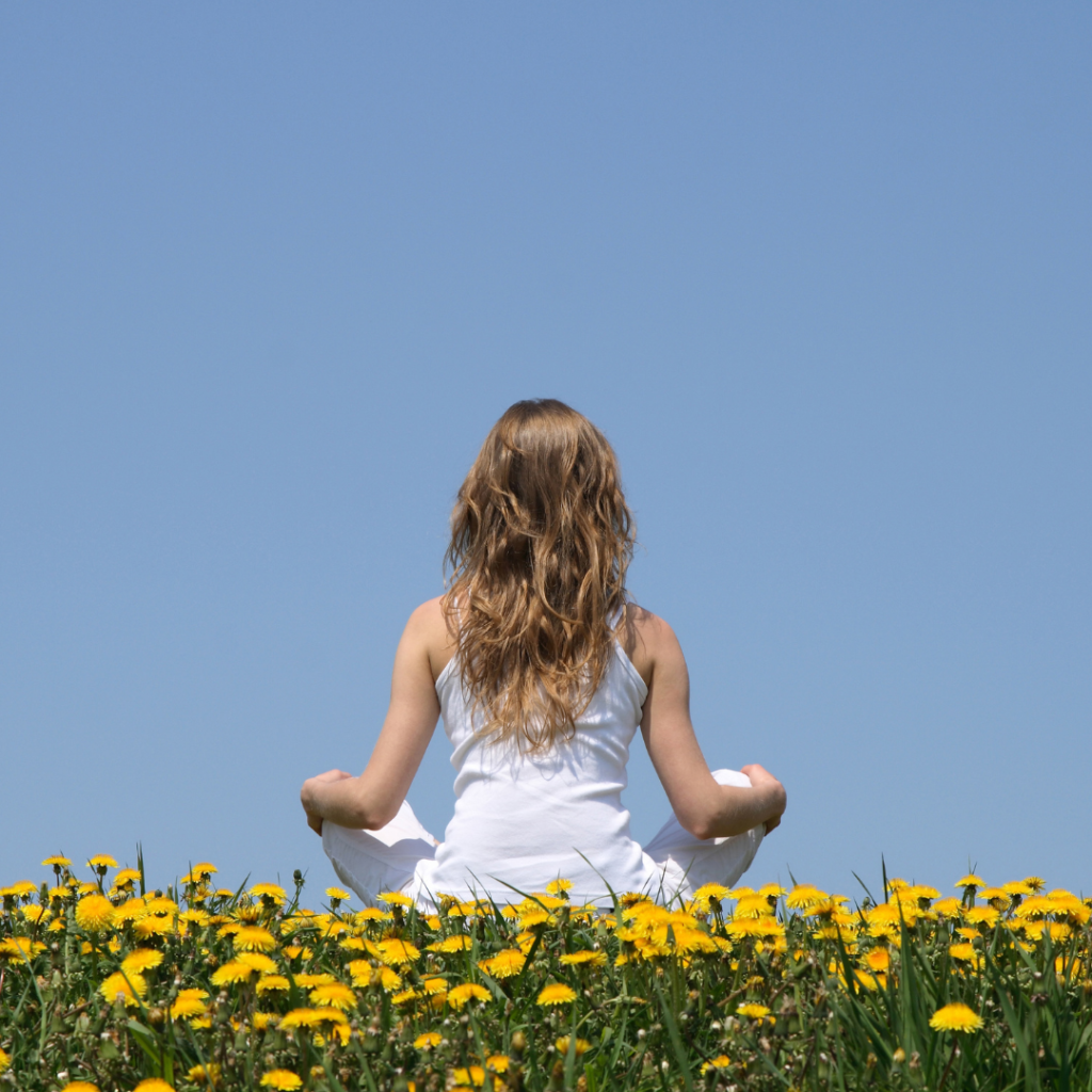 a woman meditating in a flower field
